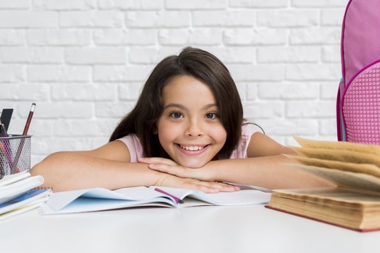 hispanic-cheerful-girl-sitting-desk