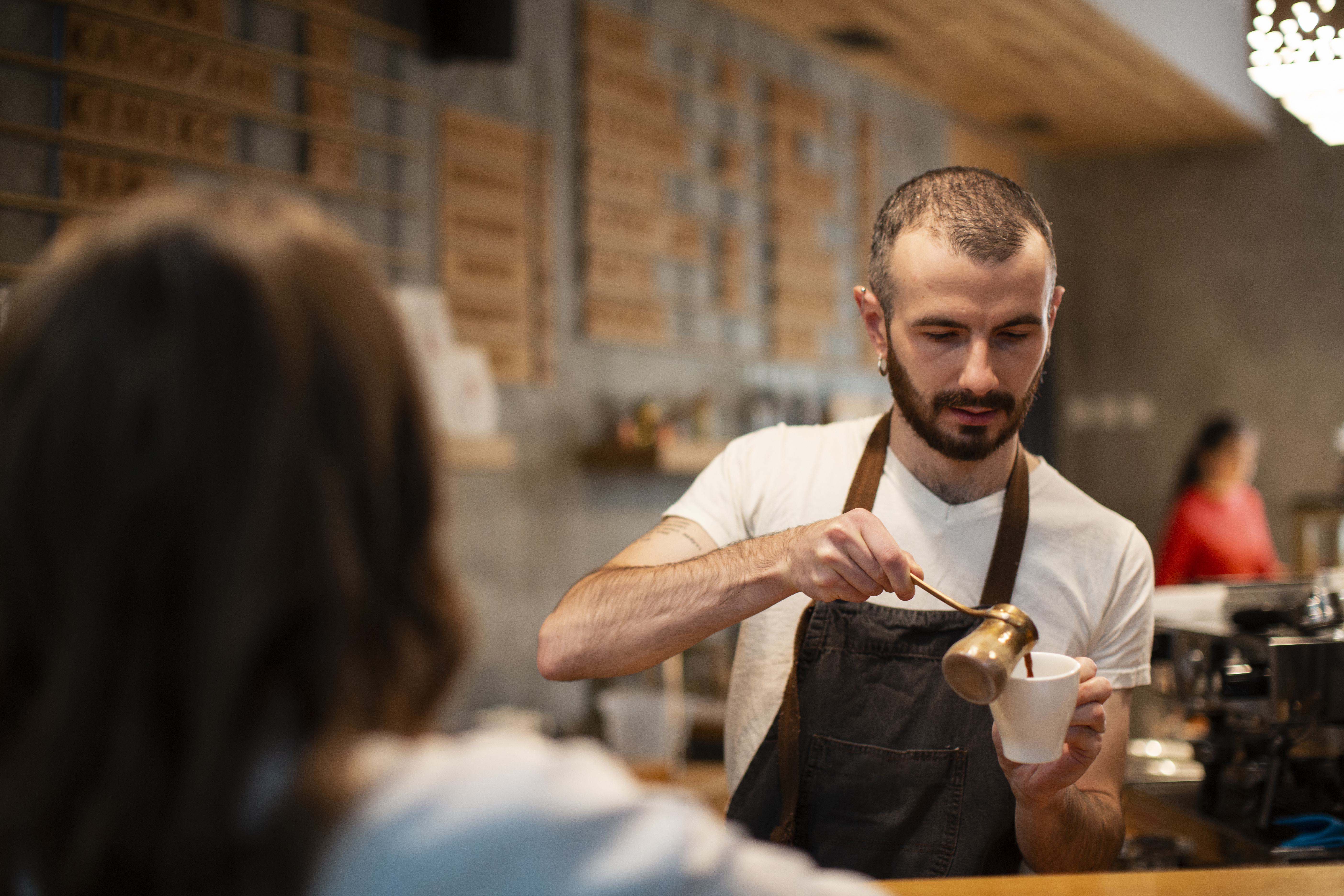 man-apron-pouring-coffee-cup-customer